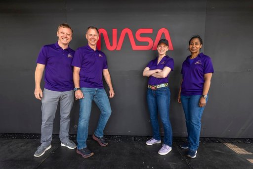 NASA's Crew-9 members stand in front of NASA’s worm logo