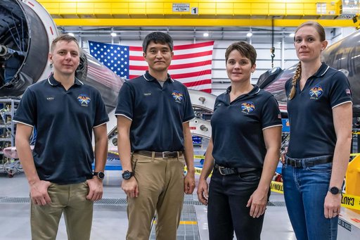 SpaceX Crew-10 members stand in front of a Falcon 9 first-stage booster
