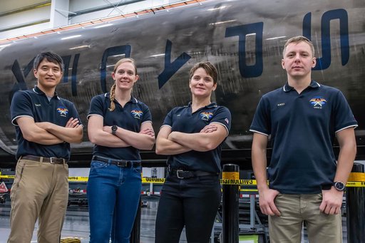 SpaceX Crew-10 members stand in front of a Falcon 9 first-stage booster