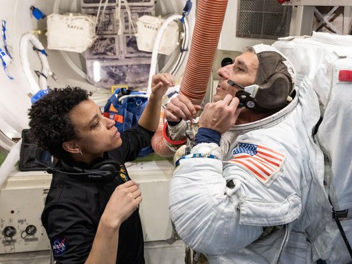 Astronaut Jessica Watkins assists astronaut Luke Delaney as he practices suiting up in a spacesuit