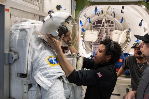 Astronaut Jessica Watkins assists astronaut Josh Kutryk as he practices suiting up in a spacesuit