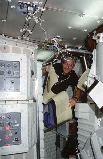 Pilot Hartsfield reviews TAGS teleprinter printout of instructions on middeck