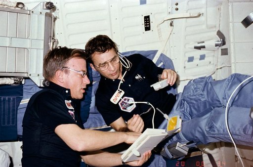 MS Peterson eats while reviewing procedures with Commander Weitz on middeck