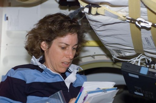 MS Ochoa reads a notebook on the middeck of Atlantis during STS-110