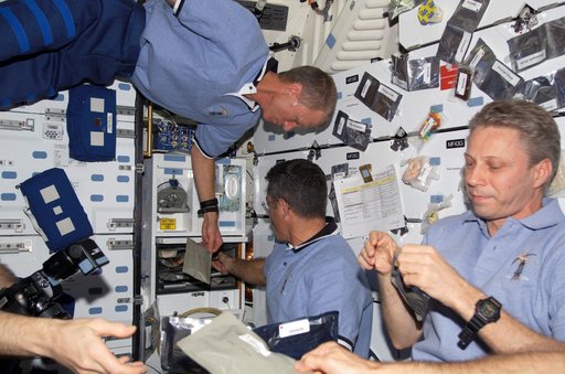 STS-115 and Expedition 13 crewmembers eating on the FWD MDDK of the Space Shuttle Atlantis