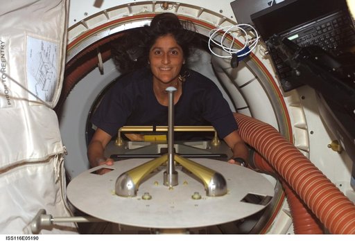 STS-116 MS Williams moves a hatch cover in the Space Shuttle Discovery