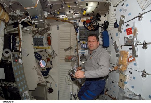STS-116 MS holding food packet in the FWD MDDK on Space Shuttle Discovery