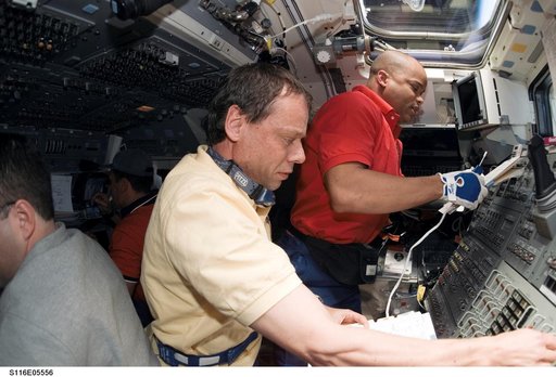 STS-116 Crewmembers work with controls in the aft FD on Space Shuttle Discovery