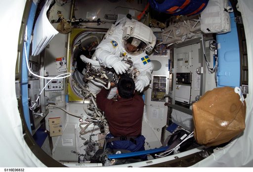 STS-116 Pilot Oefelein assists STS-116 MS Fuglesang with his EMU during Joint Operations