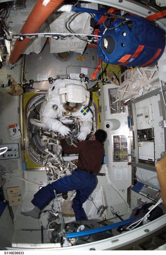 STS-116 Pilot Oefelein assists STS-116 MS Fuglesang with his EMU during Joint Operations