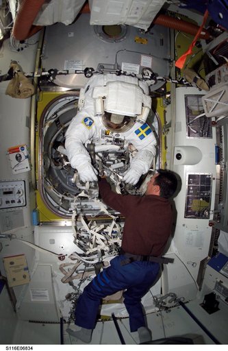 STS-116 Pilot Oefelein assists STS-116 MS Fuglesang with his EMU during Joint Operations