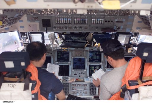 STS-116 Crewmembers Polansky and Oefelein look over crew procedures in the FWD FD on Space Shuttle Discovery