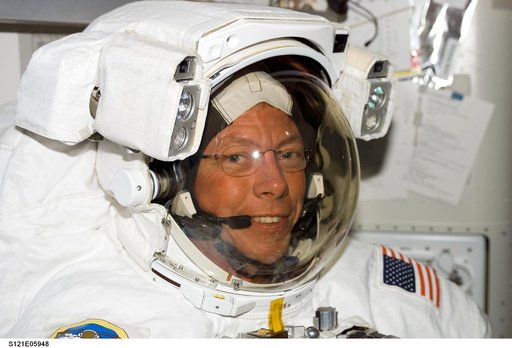 Fossum, smiles at the camera, as he wears his EMU inside the A/L before EVA1 during STS-121 / Exp. 13 joint OPS