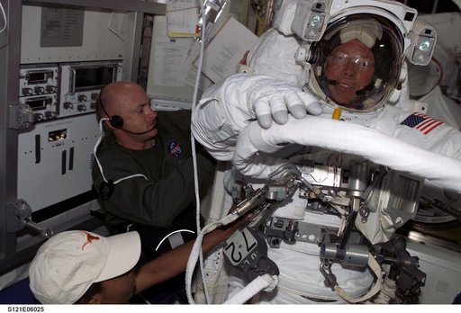 Kelly and Wilson attach the SAFER to Fossums EMU during STS-121 / Expedition 13 joint operations