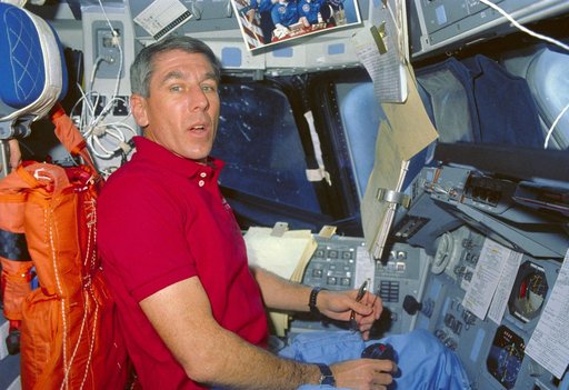 STS-29 Pilot Blaha displays photograph of crewmembers' wives on flight deck