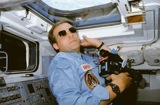 STS-30 MS Lee, wearing sunglasses, uses 70mm camera on aft flight deck