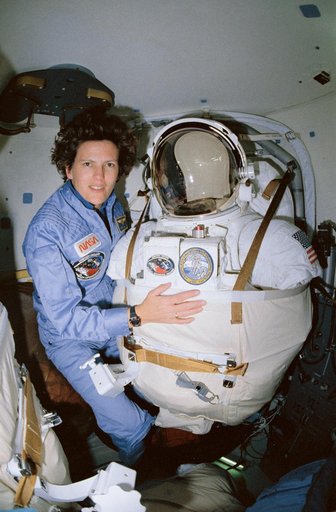 STS-31 MS Sullivan poses next to stowed EMU in OV-103's airlock