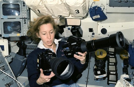 STS-32 Mission Specialist Ivins juggles camera equipment on aft flight deck