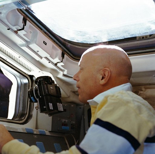 STS-33 Mission Specialist Musgrave points camera out aft flight deck window