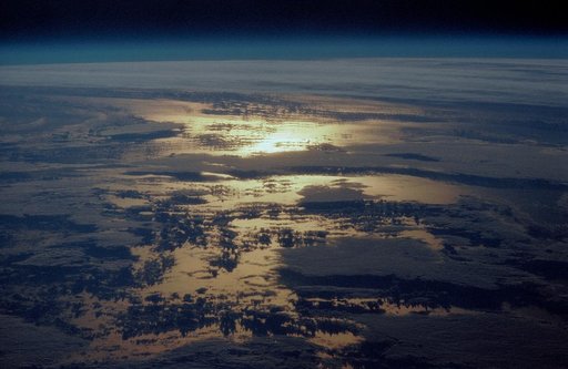 STS-36 Earth observation of sun beaming off cloud-covered ocean waters