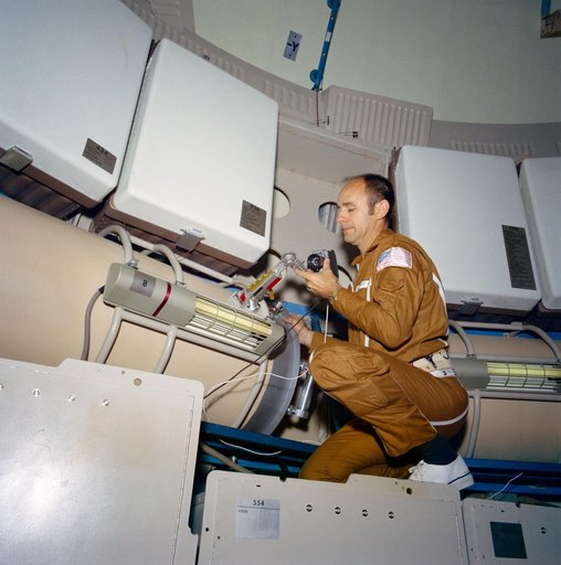 Astronaut Alan Bean looks over data acquisition camera on Skylab trainer
