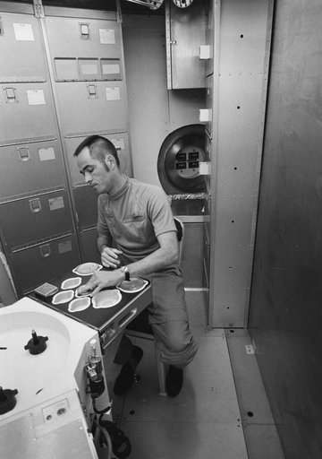 Astronaut Robert Crippen simulates preparation of Skylab meal