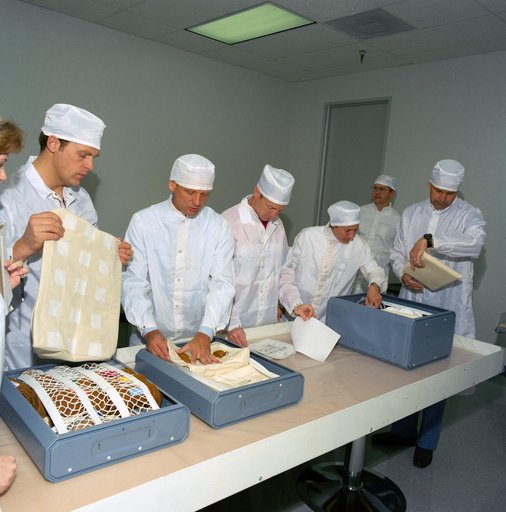 STS-30 clean-suited crewmembers examine locker contents during bench review