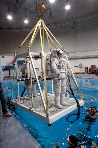 STS-39 EMU suited crewmembers are lowered into JSC's WETF Bldg 29 pool