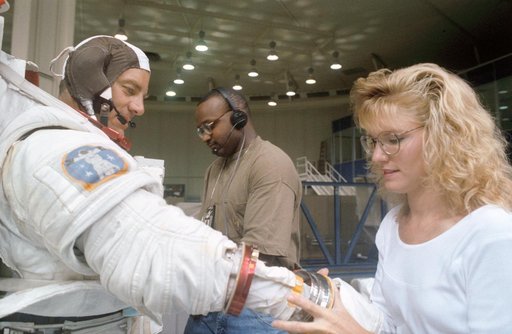 STS-53 MS Voss,in EMU, dons gloves with technicians' assistance at JSC's WETF
