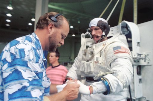 Astronaut Joseph Tanner is assisted into his EMU during training