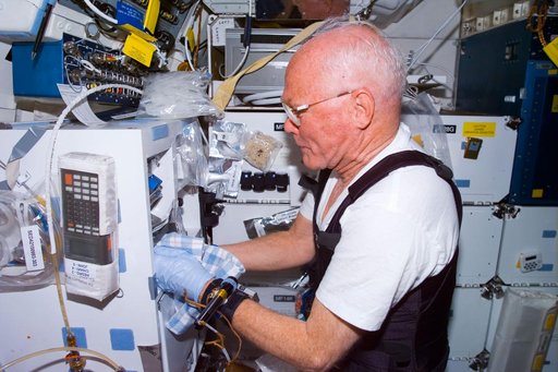 Glenn works with experiment on middeck