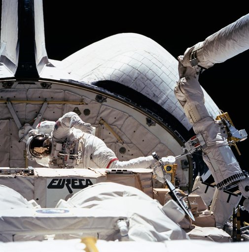 STS-57 MS & PLC Low, in EMU and atop the RMS, is maneuvered in OV-105's PLB