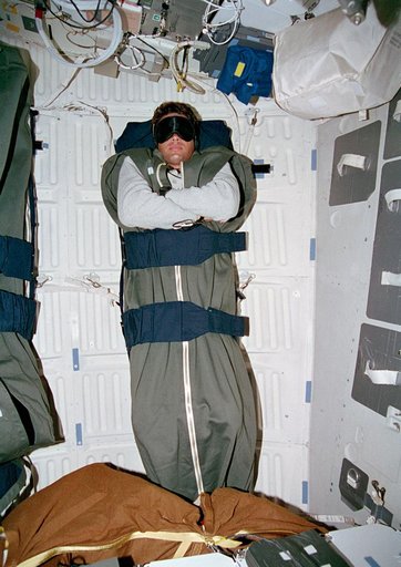 Kregel sleeping in middeck sleep restraints wearing mask