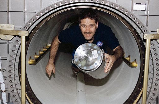 MS Grunsfeld moves freezer unit through transfer tunnel to Spacehab
