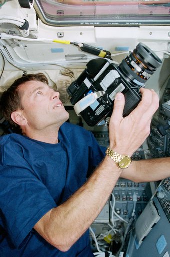 STS-93 Pilot Ashby takes some photographs of the Earth from the flight deck