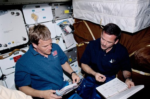 Parazynski and Hadfield look over EVA checklists on Endeavour's middeck during STS-100