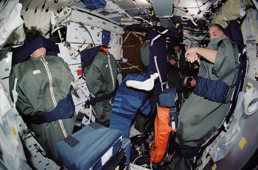 STS-112 crew in their sleep restraints on the orbiter middeck