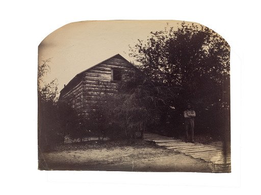 Log cabin with man standing at right