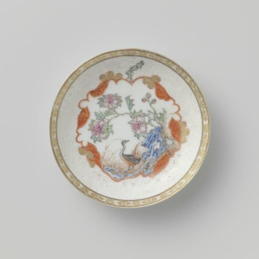 Saucer with crane near a peony plant and rock
