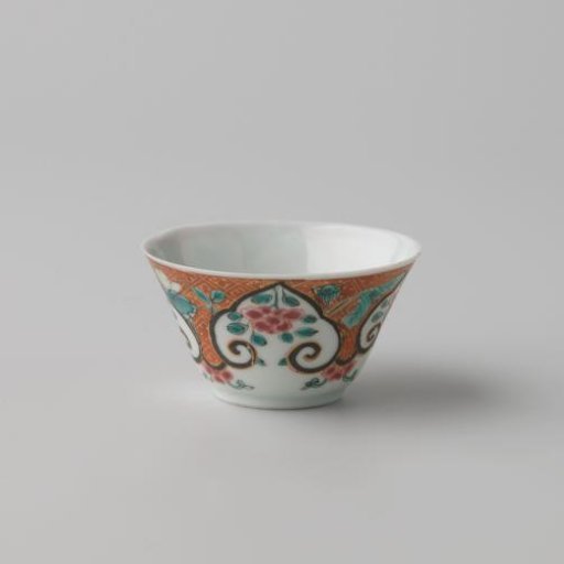 Cup with flower sprays and flowering plants on a diaper-pattern