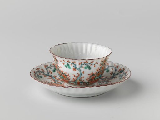 Bell-shaped cup and saucer with fluted sides with a flower basket and a tree behind a fence