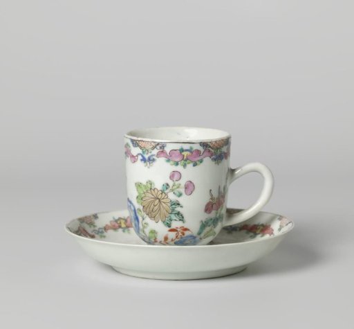 Chocolate cup and saucer with flowering plants near a rock and scrolls