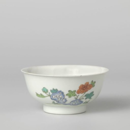Bell-shaped bowl with flower sprays and a flowering plant near a rock