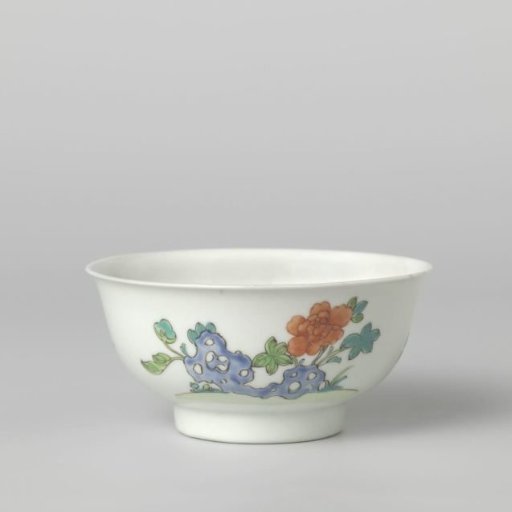 Bell-shaped bowl with flower sprays and a flowering plant near a rock