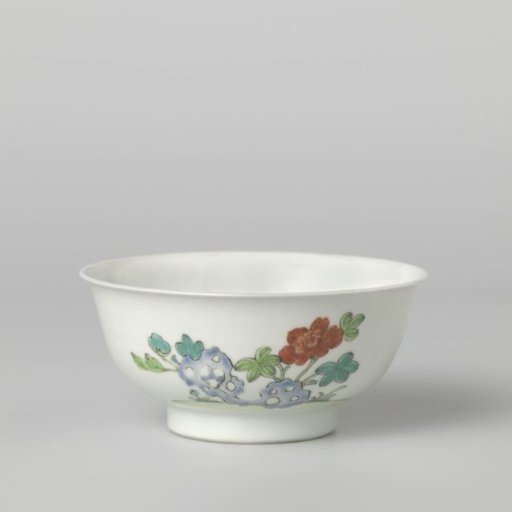 Bell-shaped bowl with flower sprays and a flowering plant near a rock