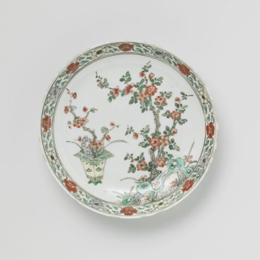 Saucer-dish with flowering plants in a flowerpot and near rocks