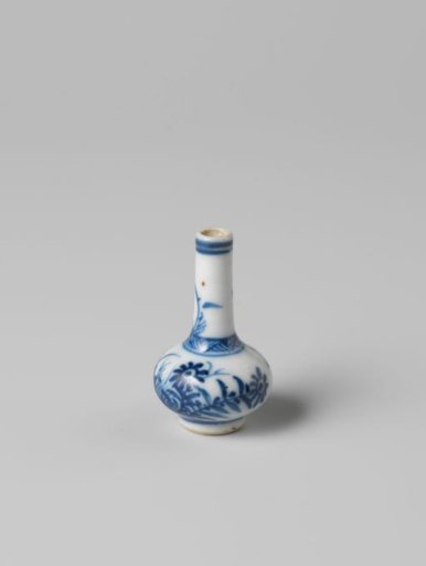 Miniature bottle vase with flowering plants and an insect near a rock
