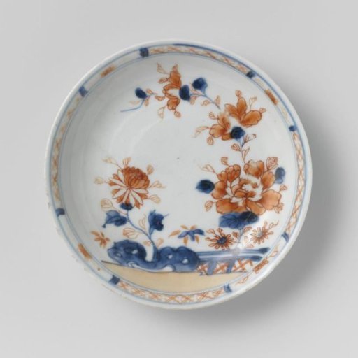 Saucer with flower sprays behind a rock and fence