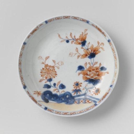 Saucer with flower sprays behind a rock and fence