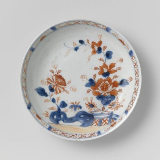 Saucer with flower sprays behind a rock and fence